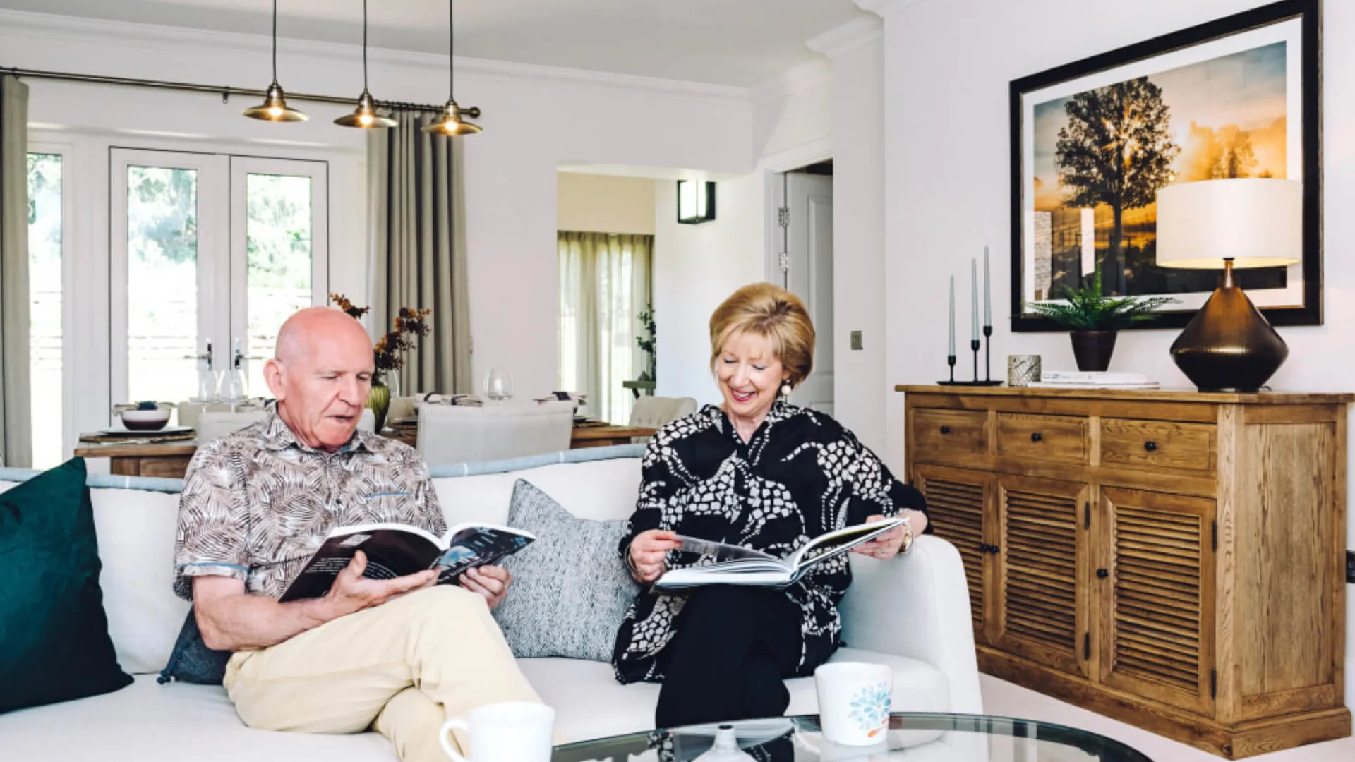 Two people sitting on a sofa reading books