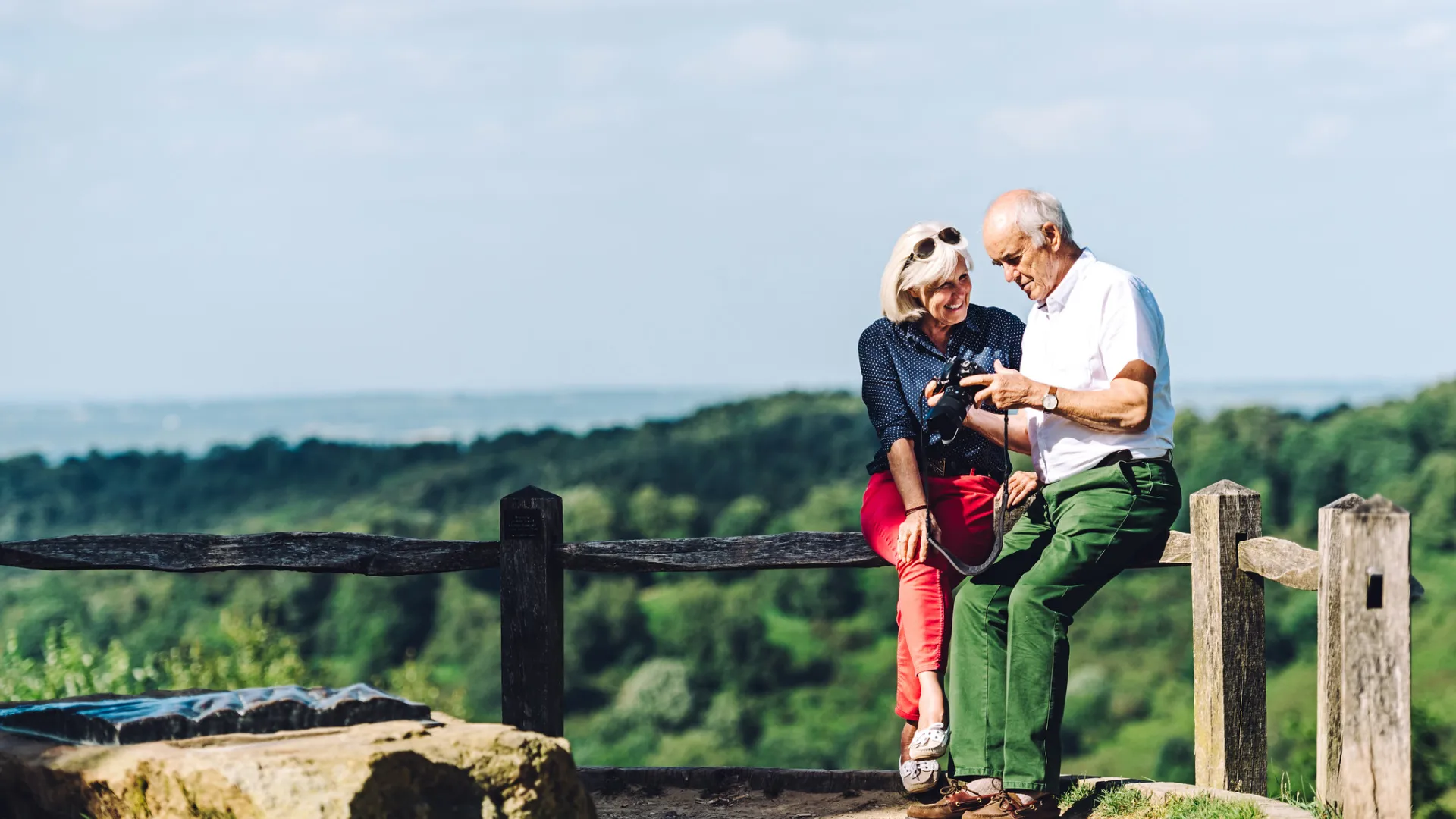 A man and women looking at a camera in the countryside
