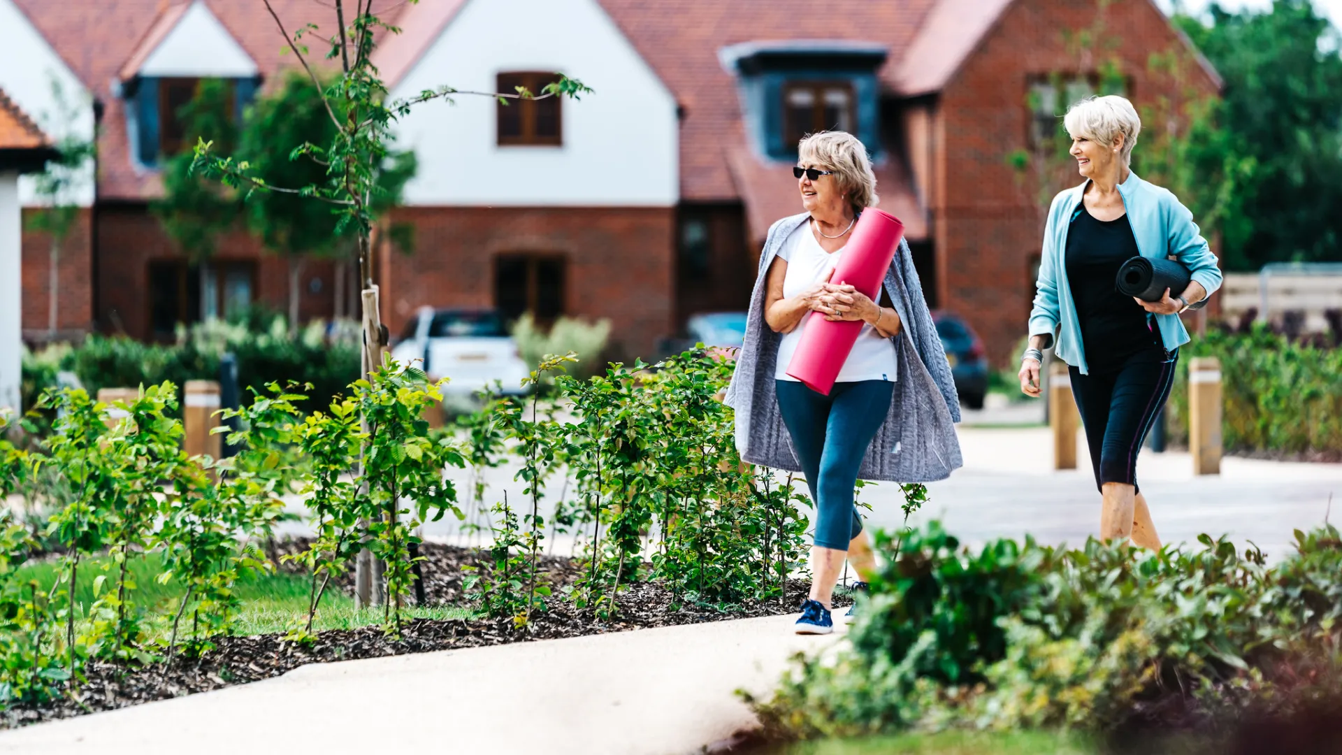 Two women walking holding yoga mats
