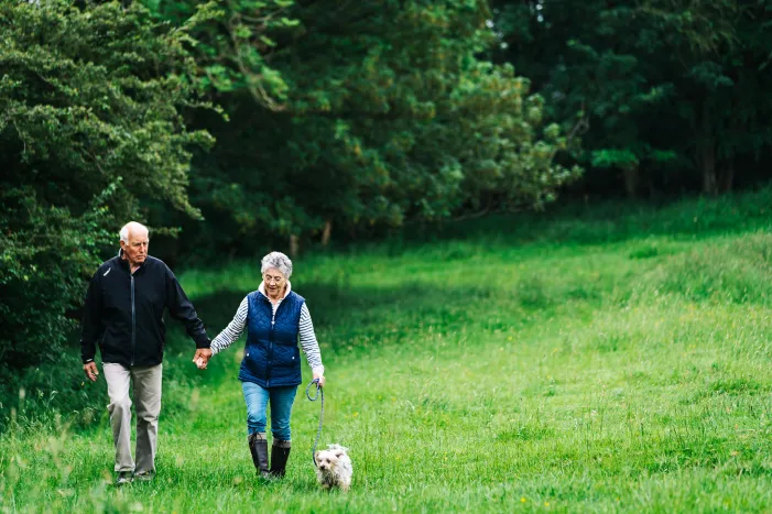 A couple walking with a dog in the countryside