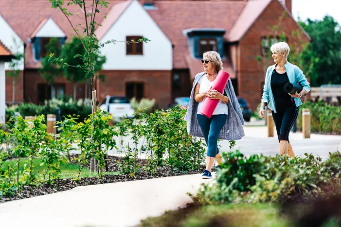 Two women walking holding yoga mats